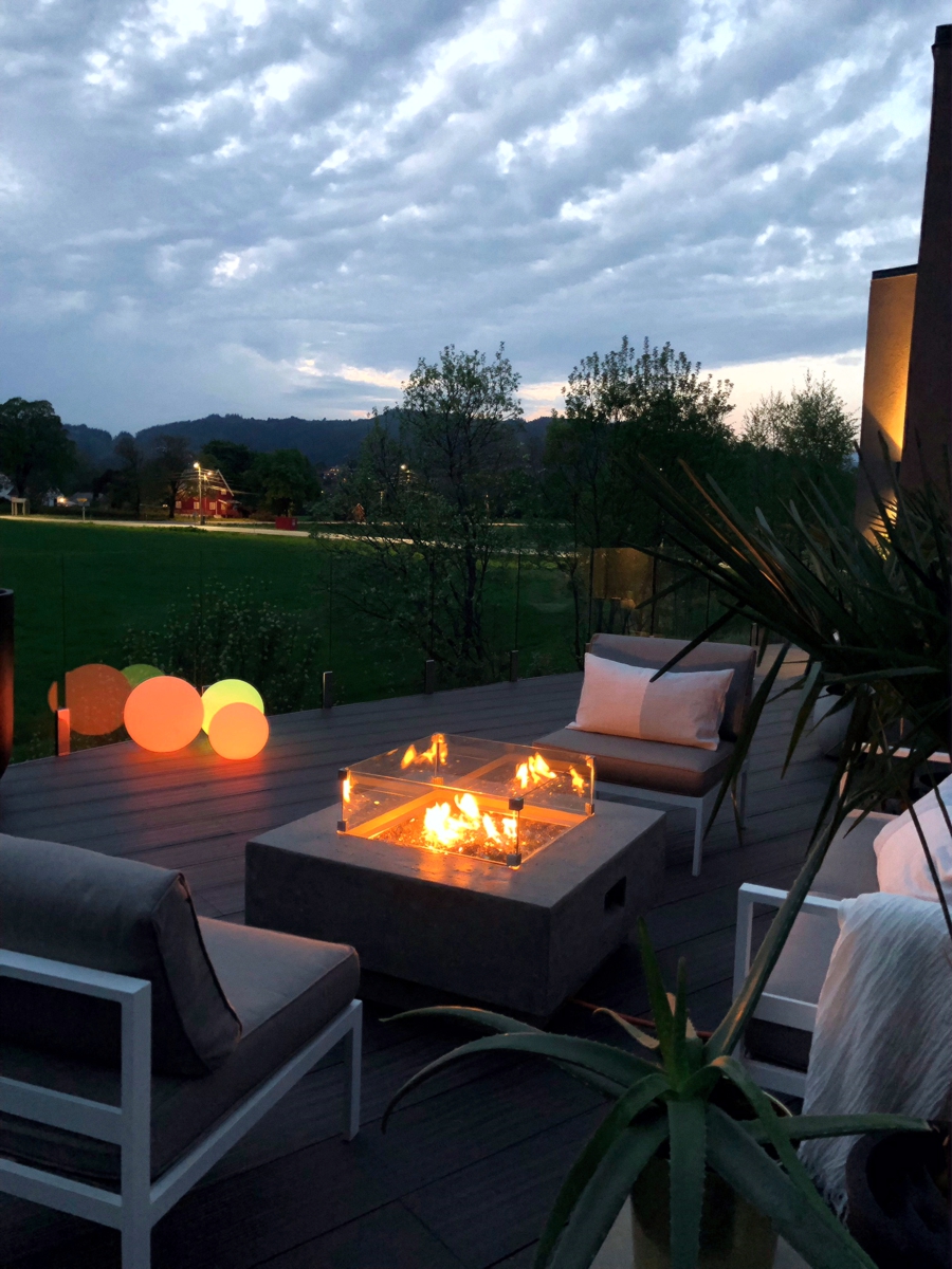 Fire pit with the glass wind guard on a terrace in the evening