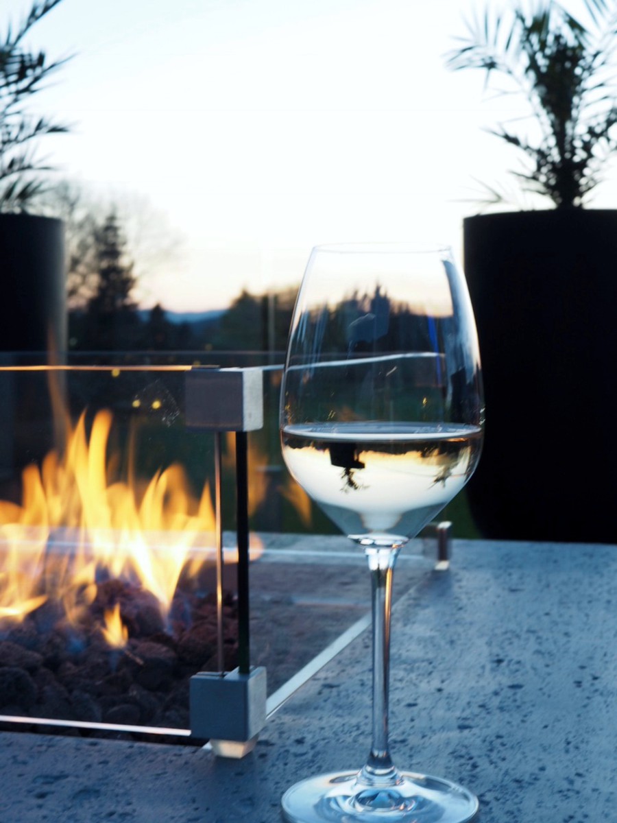 Glass wind guard by a burning fire with a glass of wine
