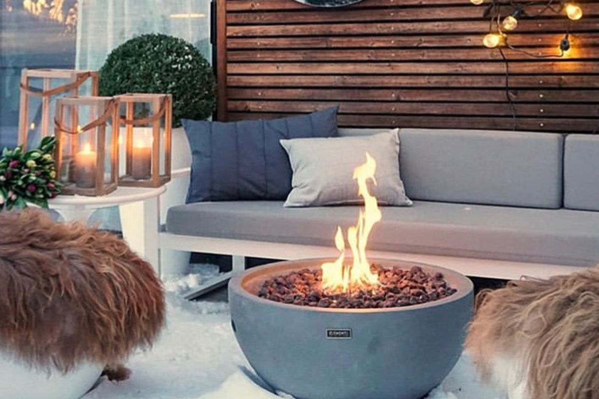 NANTUCKET fire pit with a lit fire in front of a garden sofa