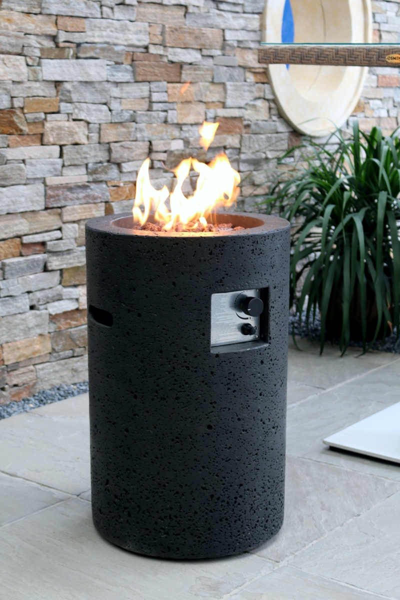 LAVA TUBE fire pit with a lit fire by a stone wall