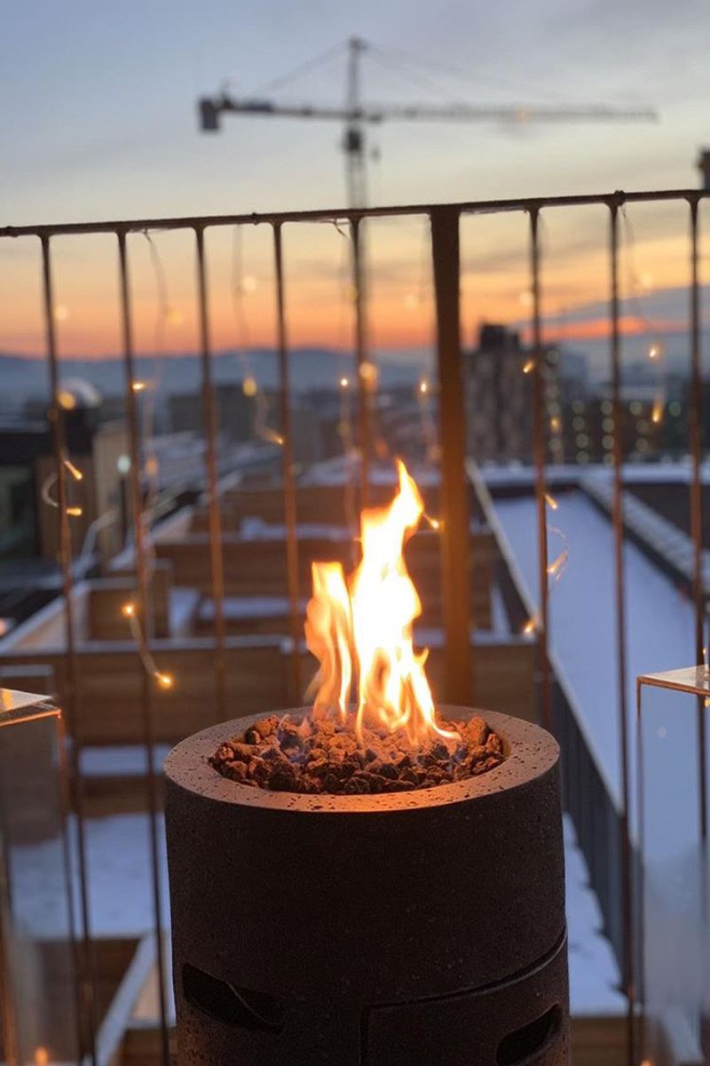 LAVA TUBE fire pit with a lit fire on a balcony at sunset