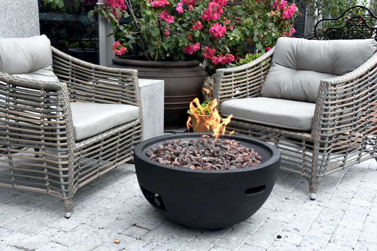 JEFFERSON fire pit with a lit fire between garden armchairs
