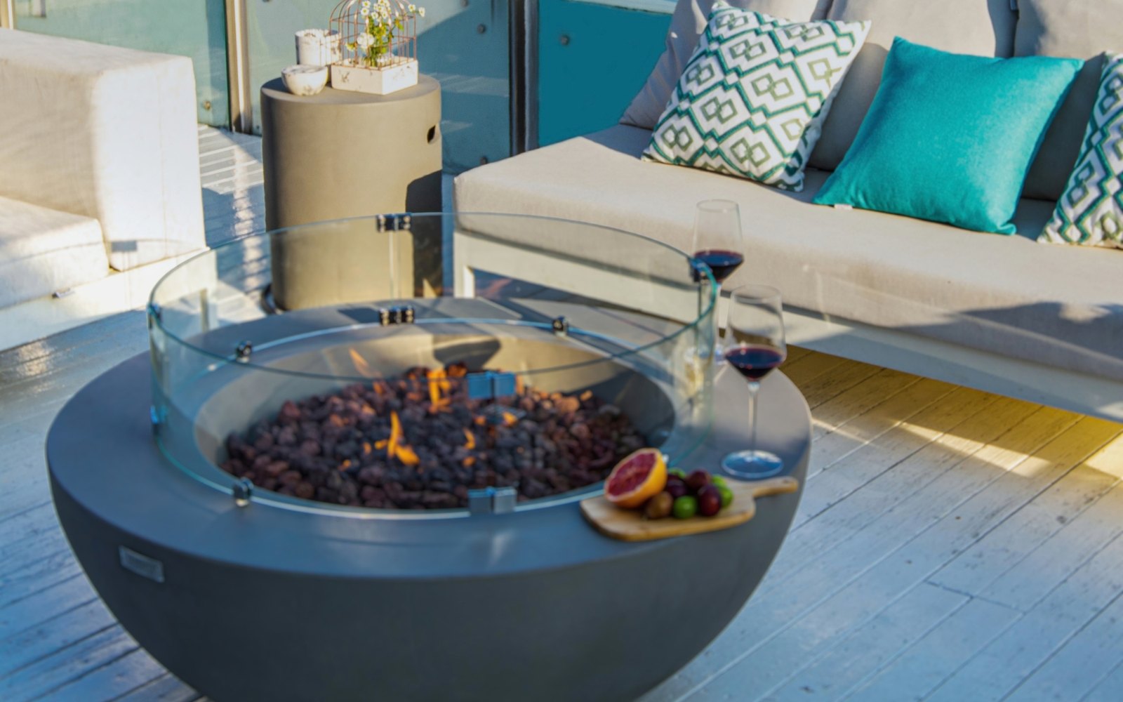 Round bottle cover next to the LUNAR BOWL fire pit on a terrace