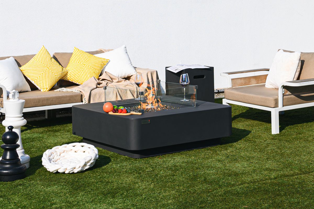 BERGAMO table with a lit fire on the lawn by a sofa