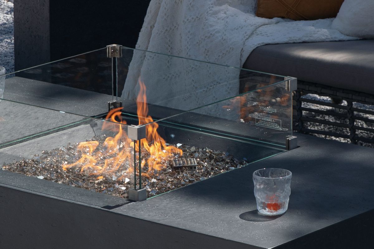 The lit fire of the CANNES table with the glass wind guard