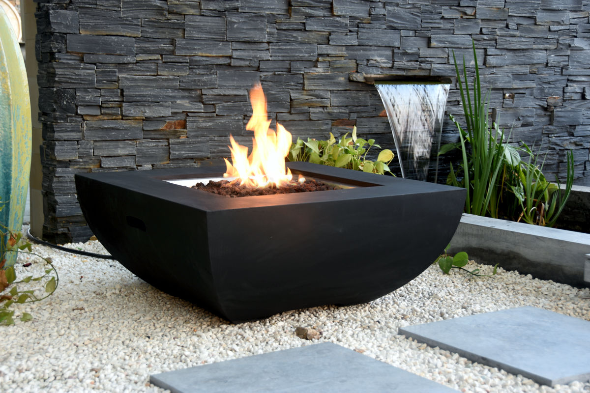 AURORA table with a lit fire pit in front of a stone wall