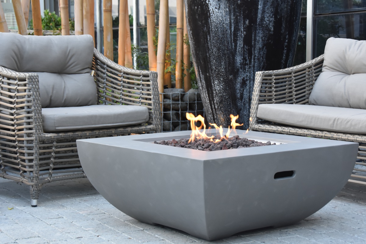 WESTPORT table with a lit fire on a terrace by rattan armchairs