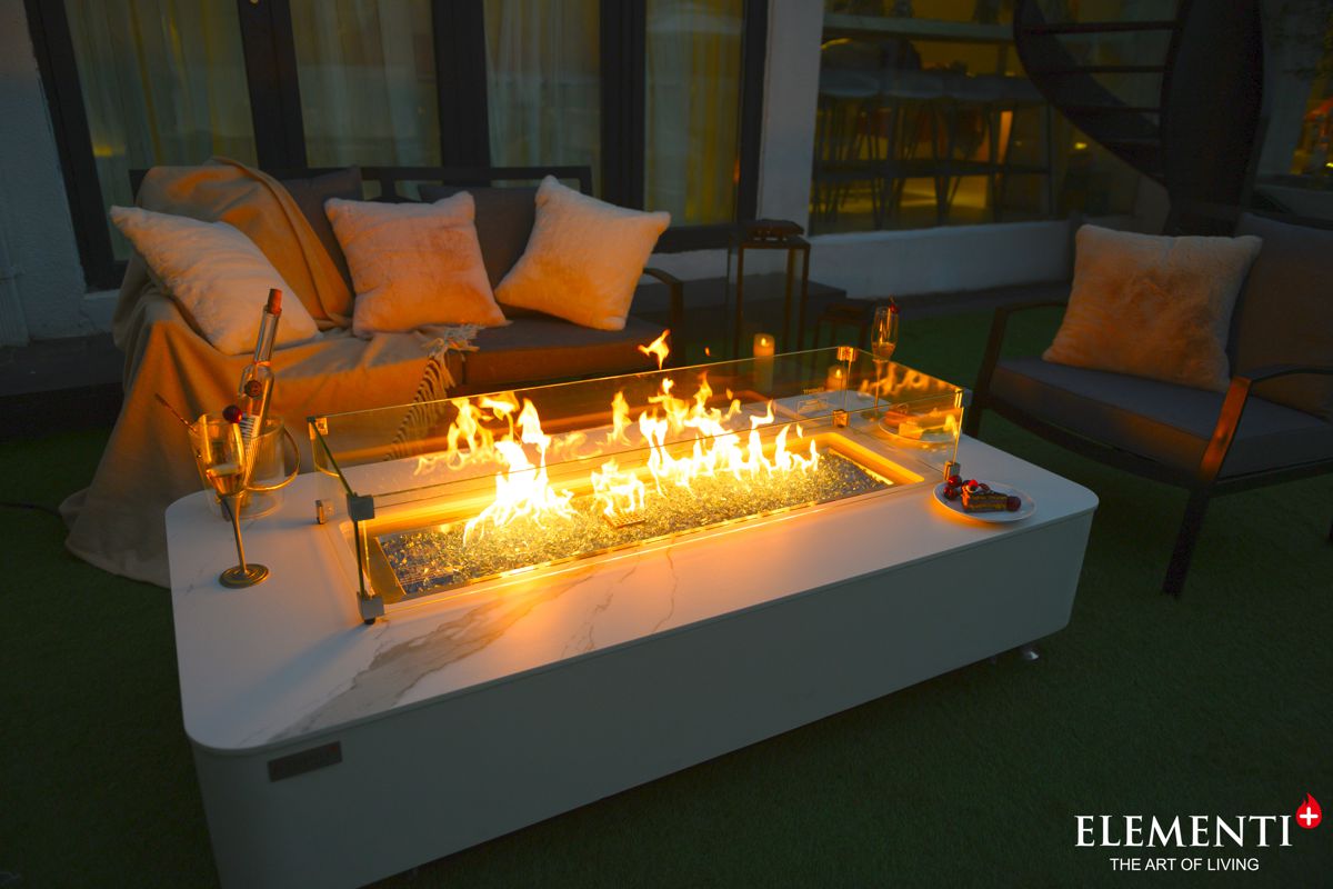 The lit fire of the ATHENS table with the glass wind guard